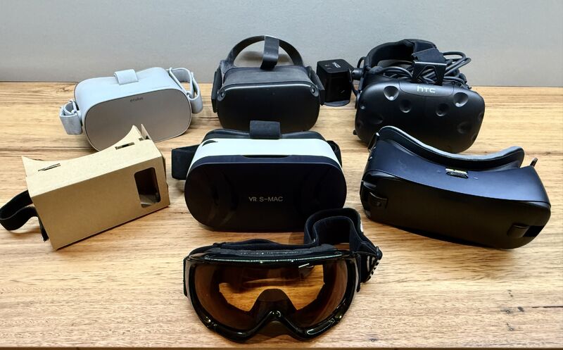 A group of VR headsets placed on a table surface, with a ski mask in the mix.